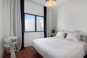 a bedroom with a white bed and a large window at Casa Loulé in Loulé