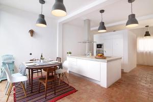 a kitchen with white cabinets and a table with chairs at Casa Loulé in Loulé +16 photos