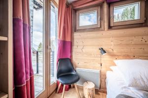 ein Schlafzimmer mit einem Bett und einem Stuhl neben einem Fenster in der Unterkunft Erin Roca immmobilier chatel boude in Châtel