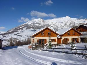 a house in the snow with mountains in the background at Deux grands chalets communicants in Les Orres