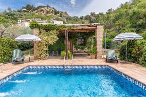 a swimming pool with two chairs and two umbrellas at La Terrera in Órgiva