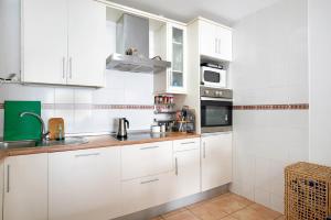 a white kitchen with white cabinets and appliances at Mirador del Palmar in Conil de la Frontera +12 photos