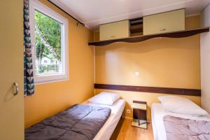 two beds in a room with a window at Mobilhome Le Tilleul in Saint-Pompont