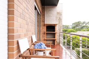 eine Veranda mit zwei Stühlen und einem Tisch mit einem Pizzaofen in der Unterkunft Fão Apart Vacation Apartments in Fão