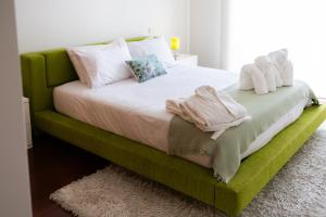 ein Schlafzimmer mit einem grünen Bett, auf dem Handtücher liegen in der Unterkunft Fão Apart Vacation Apartments in Fão + 37 Fotos