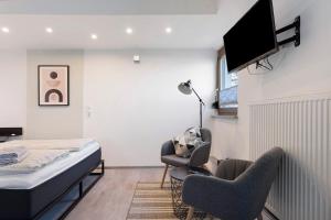 a bedroom with a bed and two chairs and a television at Ferienhaus Landliebe in Ötisheim