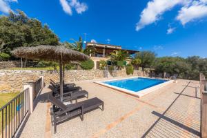 a swimming pool with two chairs and an umbrella at Taconera in Artá
