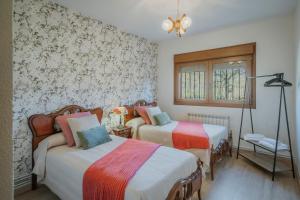 two beds in a room with floral wallpaper at El Corcal in Triollo