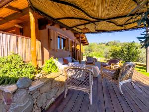 a porch with a couch and chairs on a wooden deck at Bioloco - sea, nature, pool in Castiadas
