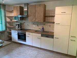 a kitchen with white cabinets and a sink at Ferienwohnung Ödbach mit Terrasse in Konzell