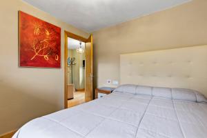 a bedroom with a white bed and a painting on the wall at El Bosque in Candamin