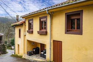 a yellow house with two windows and a door at El Bosque in Candamin