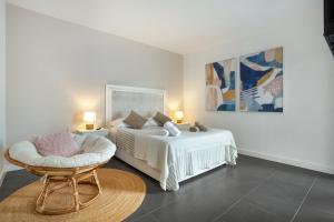 a white bedroom with a bed and a chair at vv Infinity Casilla in La Oliva +25 photos