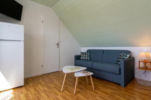 a living room with a blue couch and a table at Le Sea Bird parking piscine été in Arzon