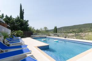 a swimming pool with blue lounge chairs next to it at Appartement N°3 - Piscine Partagée in Lagorce