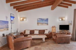 a living room with leather furniture and a tv at Ses Roques Casa del Sol in Illes Balears