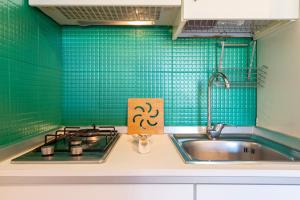 a kitchen with a sink and a stove and green tiles at Appartamento Cerri in Badesi +14 photos