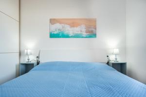 a white bedroom with a blue bed with two tables at Appartamento Cerri in Badesi