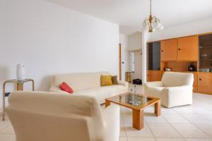 a living room with two white chairs and a coffee table at Appartamento Leo in Brindisi