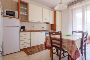 a kitchen with white cabinets and a table with chairs at Appartamento Leo in Brindisi +6 photos
