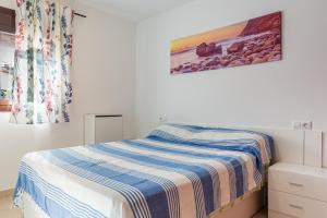 a bedroom with a bed with a striped blanket at Can Maryel in Tossa de Mar