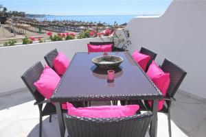 a table and chairs with pink pillows on a balcony at Deluxe Apartment on the Beach in Marbella