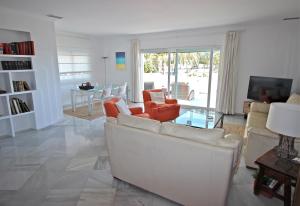 a living room with a white couch and orange chairs at Deluxe Apartment on the Beach in Marbella