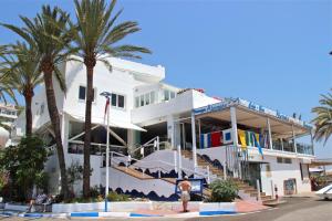 a white building with palm trees in front of it at Deluxe Apartment on the Beach in Marbella