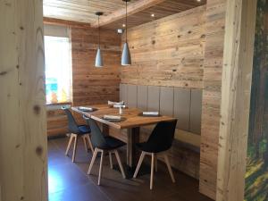 a dining room with wooden walls and a wooden table and chairs at Fedaia Joy Bnb in Canazei