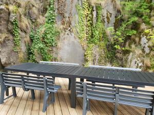 a table and benches on a deck with a wall at Vacance 16 Pers in La Bourboule