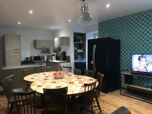 a kitchen with a table with chairs and a television at Vacance 16 Pers in La Bourboule