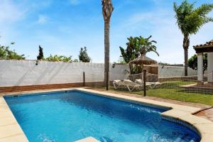 a swimming pool in a backyard with a fence and palm trees at Casa Ale in Cádiz