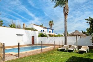 a villa with a swimming pool and a palm tree at Casa Ale in Cádiz