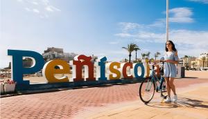 a woman standing next to a bike in front of a sign at Perlazul in Peniscola