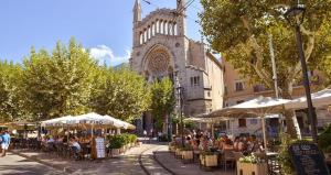 a group of people sitting at tables in front of a church at Villa Can Got in Sóller