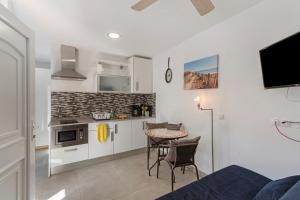 a kitchen with white cabinets and a table with chairs at Casa Paula - 21 in Arinaga