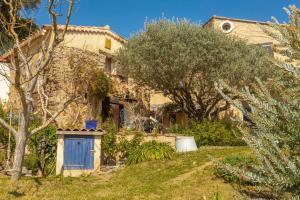 an old stone house with a blue door in a garden at La Fenière - Maison avec terrasse in Collobrières