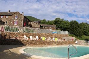 a swimming pool in front of a stone wall and a building at Maison Jordan - Mas Lachamp in Gravières