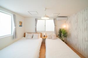 two beds in a room with white walls and windows at 照間Terumaの美しい海と太陽 Soleが目前に広がる和室ありの宿 TERUSOLEテルソーレ in Uruma
