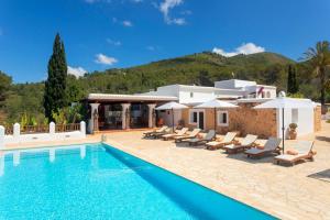 a villa with a swimming pool and lounge chairs at Can Pep Den Sitges in Sant Joan de Labritja