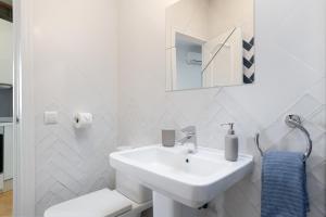 a white bathroom with a sink and a mirror at Casa Buganvilla in Barbate +13 photos