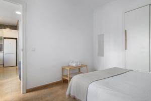 a white bedroom with a bed and a table at Casa Buganvilla in Barbate