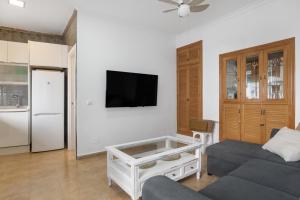 a living room with a couch and a tv on a wall at Casa Buganvilla in Barbate