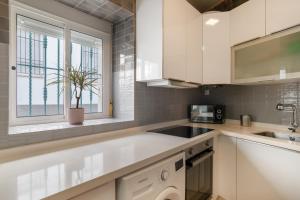 a kitchen with white cabinets and a sink and a window at Casa Buganvilla in Barbate