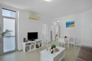 a white living room with a tv and a table at Vv Brisamar in Telde