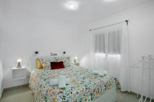a white bedroom with a large bed with a red pillow at Vv Brisamar in Telde