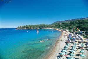 a beach with umbrellas and people in the water at App Casa Dei Pini - Bilocale in Capoliveri