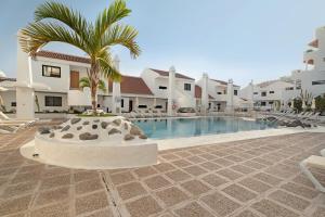 a swimming pool with a palm tree in front of a building at Penthause Luxe 501 sea View pool in Playa Fañabe