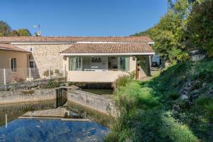 a house with a pond in front of it at Gite du Moulin - Ariège in Carla-de-Roquefort