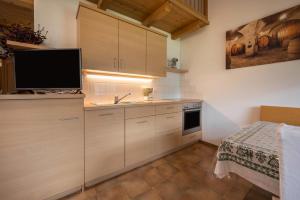 a kitchen with wooden cabinets and a flat screen tv at Kreuzhof links in Novacella +16 photos
